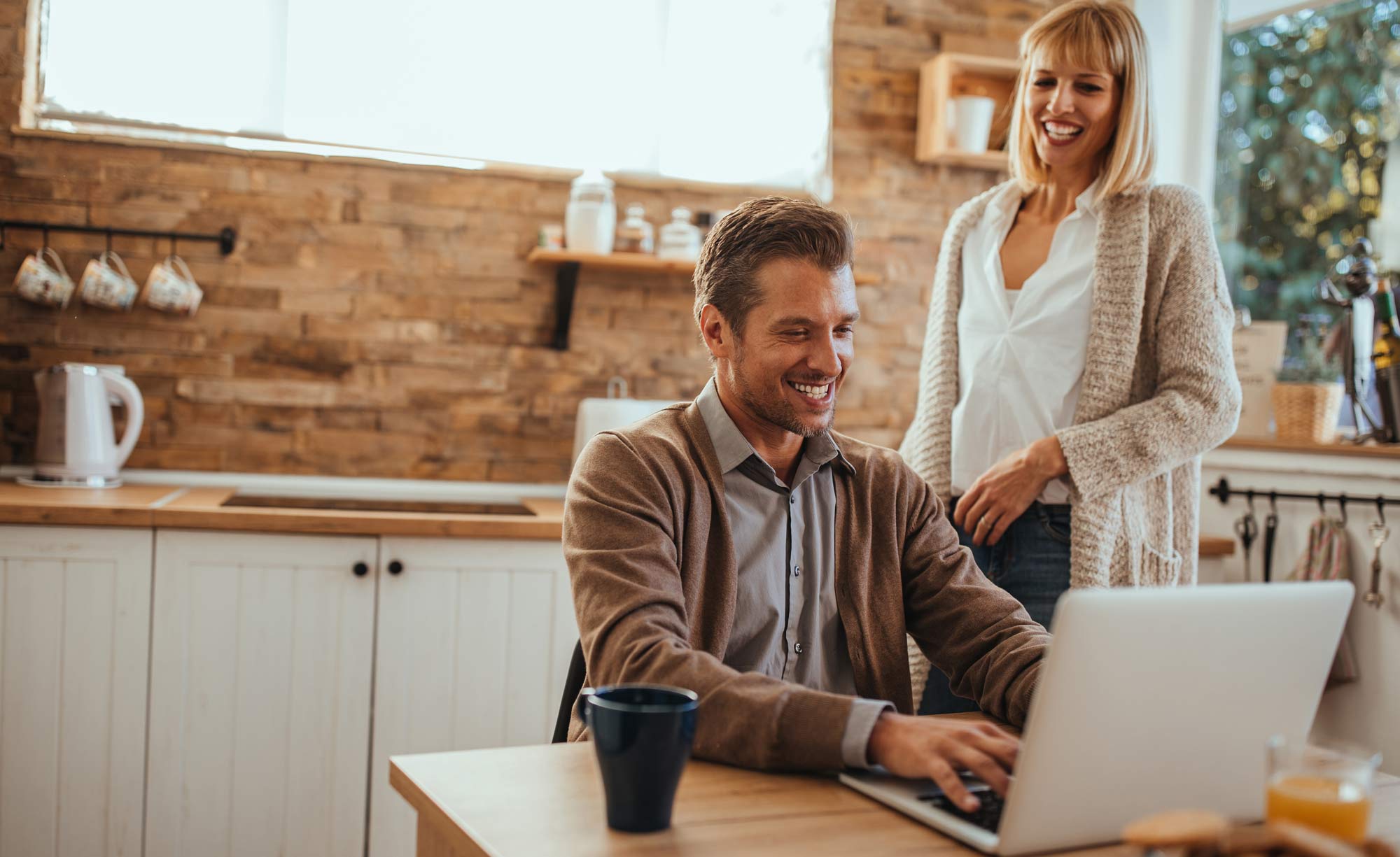 A couple look happily at their application for a low interest debt consolidation loan on a laptop