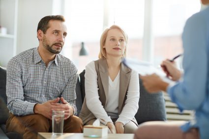 Debt: Understanding Good Debt and Bad Debt | DCL Young couple sitting on couch in front of psychologist and listening to her advice at meeting